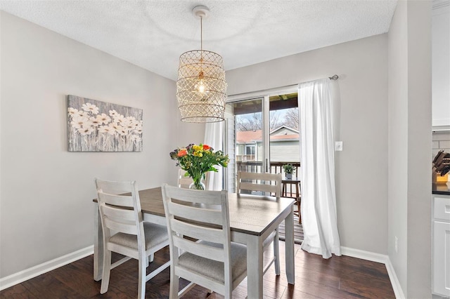 dining room featuring dark wood-style floors, a chandelier, a textured ceiling, and baseboards