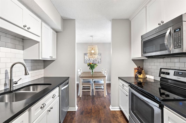 kitchen with dark countertops, white cabinetry, appliances with stainless steel finishes, and a sink