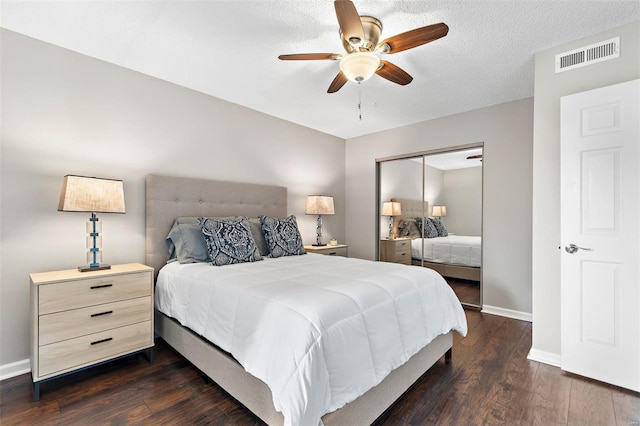 bedroom with a closet, visible vents, dark wood finished floors, and baseboards