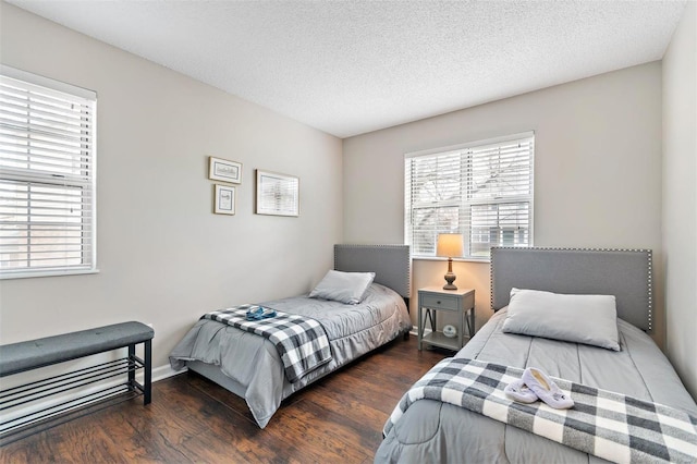 bedroom with dark wood-style floors, a textured ceiling, and baseboards