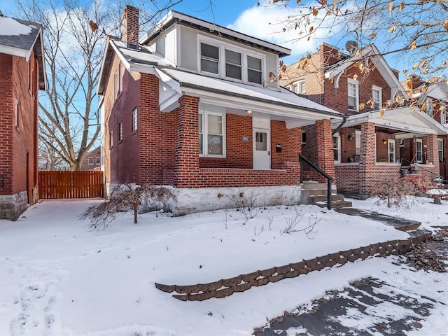 view of front facade with a chimney, fence, and brick siding