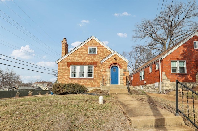 view of front of house with a front yard, a chimney, fence, and brick siding