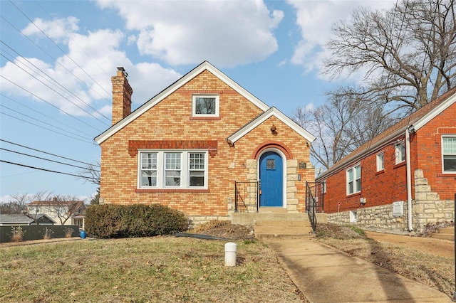 view of front of home featuring a front yard, a chimney, and brick siding