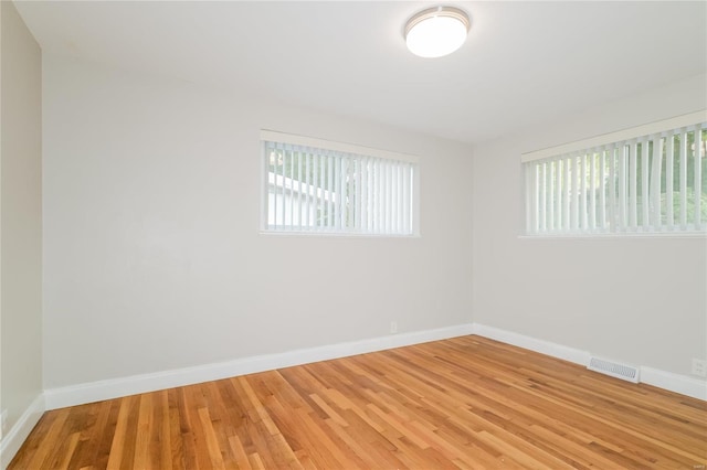 empty room featuring light wood-style floors, visible vents, and baseboards