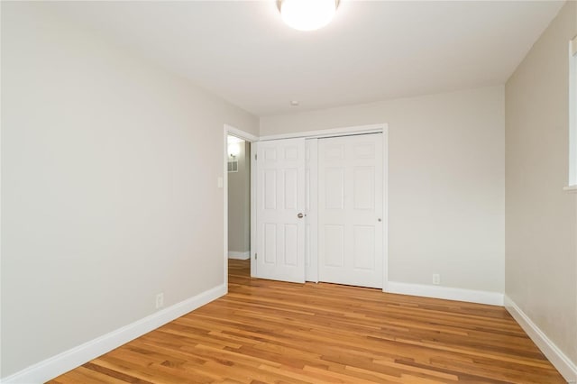 unfurnished bedroom with a closet, baseboards, and light wood finished floors