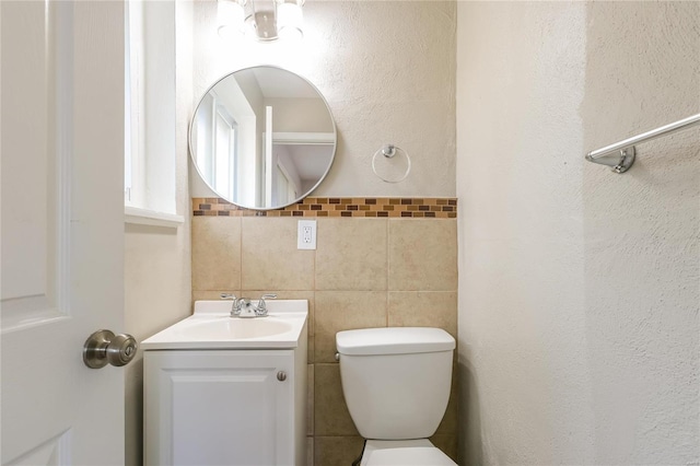 bathroom featuring toilet, tile walls, and vanity