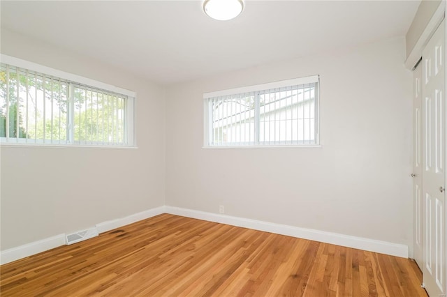 empty room featuring baseboards, a healthy amount of sunlight, and light wood finished floors