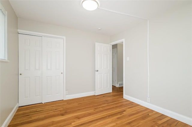 unfurnished bedroom with a closet, light wood-type flooring, and baseboards