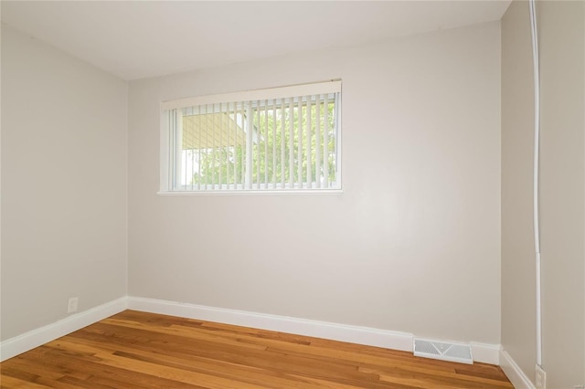 spare room with baseboards, visible vents, and wood finished floors