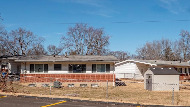 view of front of property with central air condition unit, fence private yard, a front lawn, and an outbuilding