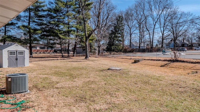 view of yard featuring a storage unit, an outdoor structure, cooling unit, and fence