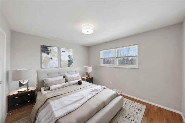 bedroom featuring visible vents, baseboards, and wood finished floors