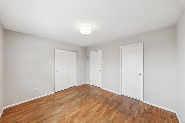 unfurnished bedroom with a closet, light wood-style flooring, and baseboards