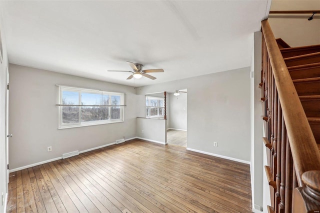 empty room featuring visible vents, hardwood / wood-style floors, ceiling fan, baseboards, and stairs