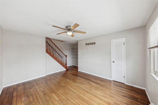 spare room with baseboards, visible vents, ceiling fan, stairway, and hardwood / wood-style floors