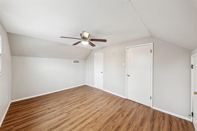 bonus room with lofted ceiling, visible vents, a ceiling fan, wood finished floors, and baseboards