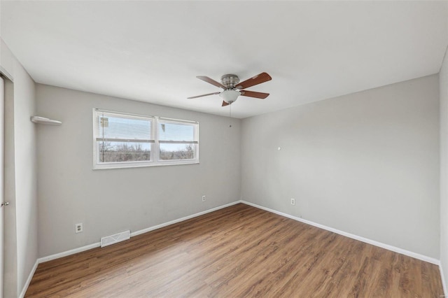 spare room featuring ceiling fan, wood finished floors, visible vents, and baseboards