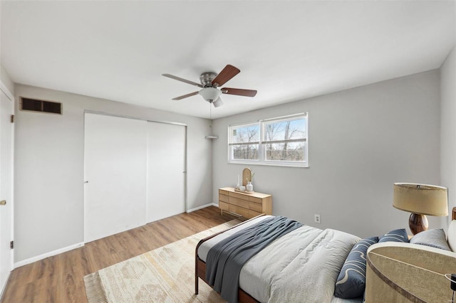 bedroom featuring baseboards, visible vents, ceiling fan, wood finished floors, and a closet