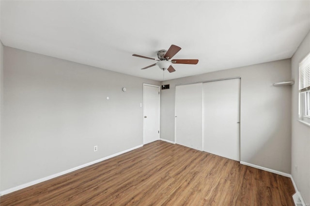 unfurnished bedroom with a closet, wood finished floors, and baseboards