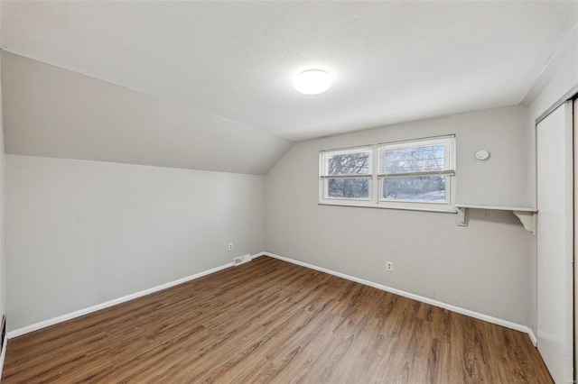 additional living space featuring visible vents, baseboards, vaulted ceiling, and wood finished floors