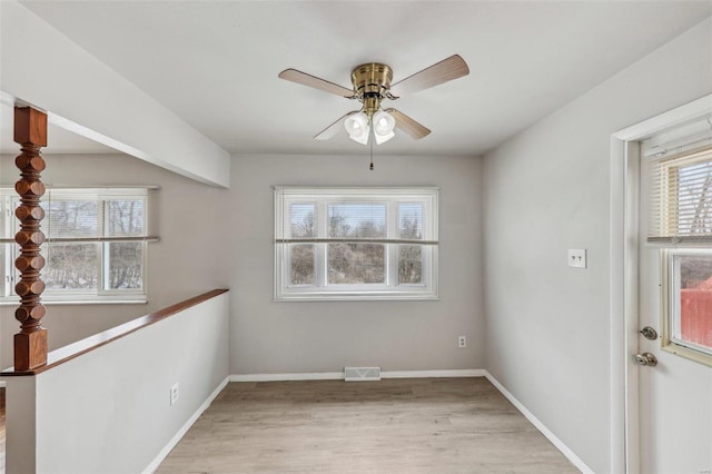 unfurnished room featuring light wood-style floors, visible vents, baseboards, and a ceiling fan