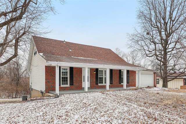 view of front facade featuring a shingled roof, covered porch, brick siding, and an attached garage