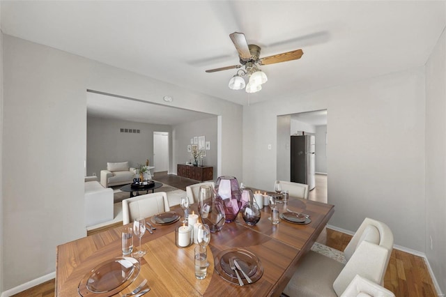 dining area with a ceiling fan, wood finished floors, visible vents, and baseboards