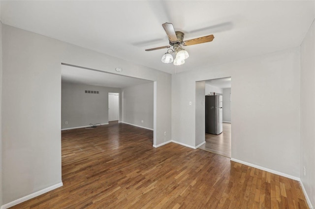 empty room with baseboards, visible vents, ceiling fan, and wood finished floors