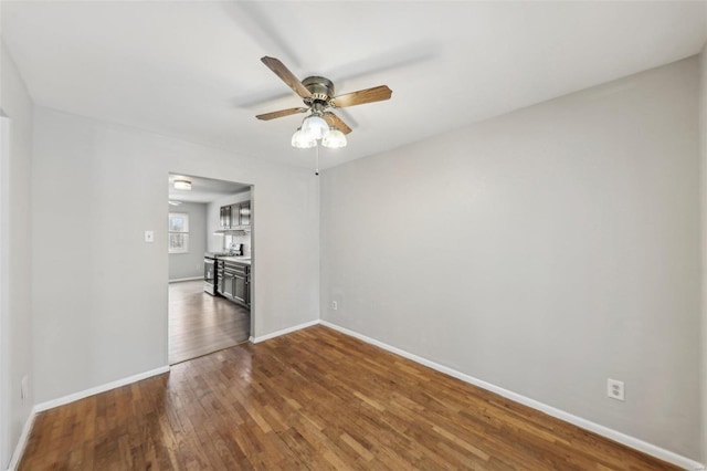 empty room with ceiling fan, baseboards, and wood finished floors