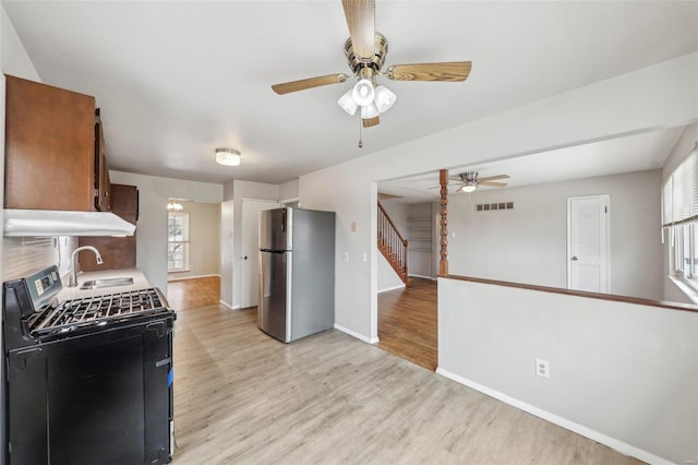 kitchen with visible vents, gas range, light wood-style flooring, freestanding refrigerator, and a sink