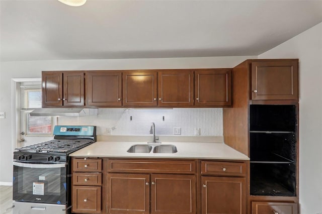 kitchen featuring light countertops, stainless steel gas range, a sink, and under cabinet range hood