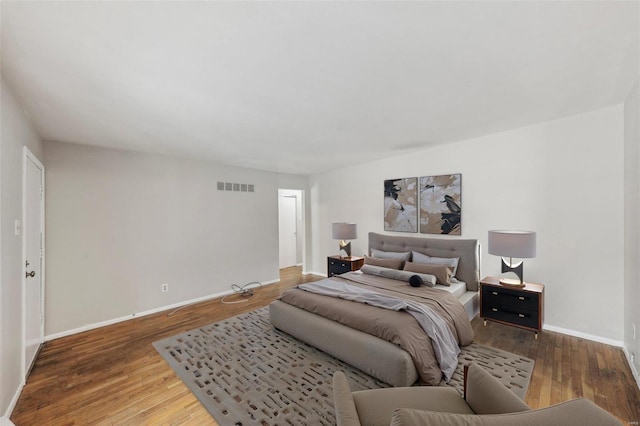 bedroom featuring wood finished floors, visible vents, and baseboards