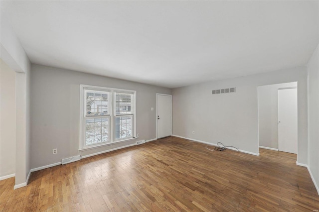 unfurnished room featuring wood finished floors, visible vents, and baseboards