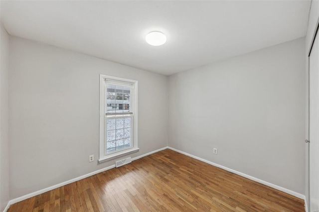 unfurnished room featuring visible vents, hardwood / wood-style flooring, and baseboards