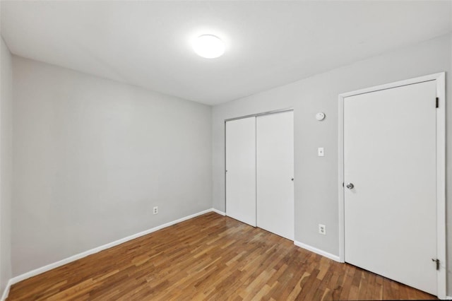 unfurnished bedroom featuring a closet, baseboards, and wood finished floors