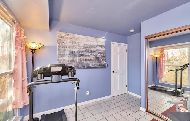 exercise room featuring light tile patterned floors and baseboards