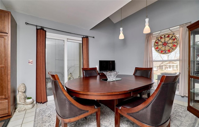 dining area with light tile patterned floors and vaulted ceiling