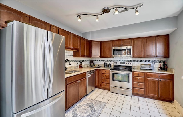 kitchen featuring light countertops, appliances with stainless steel finishes, backsplash, and a sink