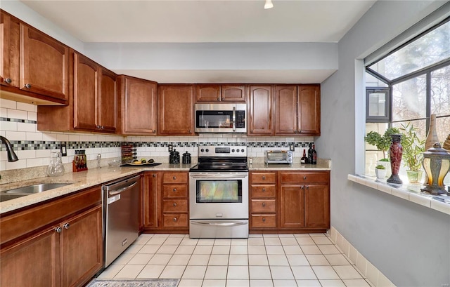 kitchen with brown cabinetry, plenty of natural light, stainless steel appliances, and a sink