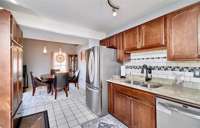 kitchen featuring pendant lighting, brown cabinets, stainless steel appliances, decorative backsplash, and a sink