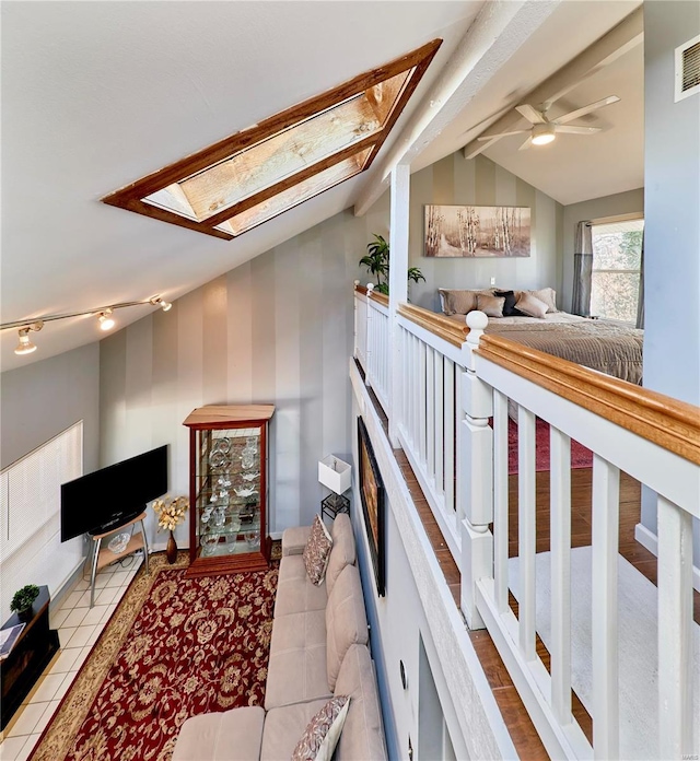 hallway with light tile patterned floors and vaulted ceiling with skylight