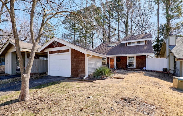 view of front of house featuring an outbuilding, a shingled roof, an attached garage, and fence