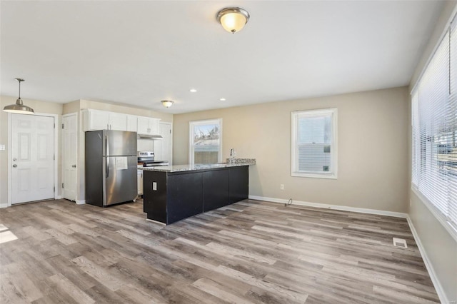 kitchen with a peninsula, wood finished floors, visible vents, white cabinetry, and appliances with stainless steel finishes