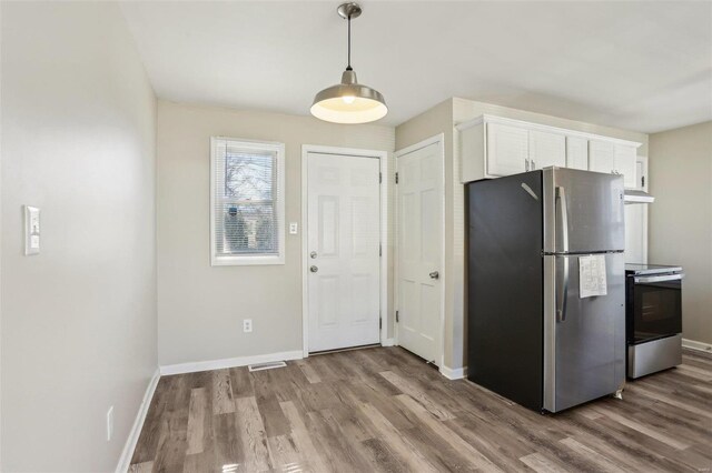 kitchen featuring baseboards, white cabinets, wood finished floors, stainless steel appliances, and under cabinet range hood