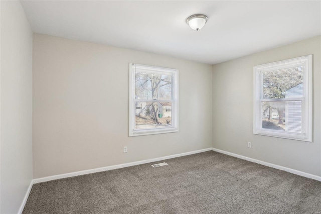 spare room featuring carpet, visible vents, and baseboards