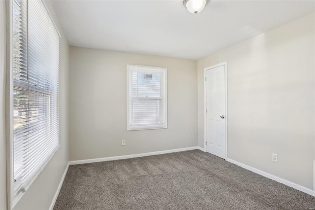 carpeted empty room featuring baseboards