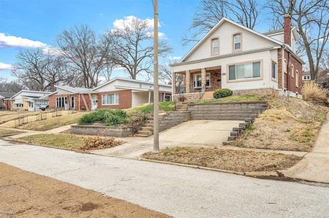 view of front of house with brick siding, a chimney, stucco siding, a porch, and stairway