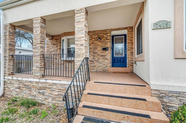 property entrance with stone siding, a porch, and stucco siding