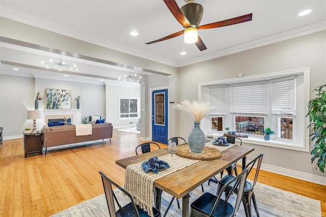 dining space featuring recessed lighting, a fireplace, baseboards, light wood-style floors, and ornamental molding