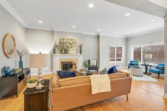 living area featuring ornamental molding, a glass covered fireplace, and light wood-style flooring